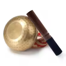 Hand-hammered Tibetan singing bowl with red cushion and wooden mallet for meditation and sound healing